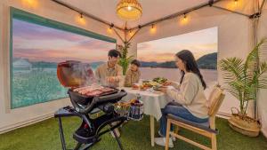a family sitting at a table in a tent with a grill at Chuncheon El Dorado Kid's Pension in Gapyeong