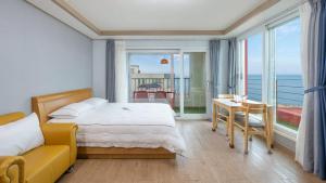 a bedroom with a bed and a view of the ocean at Gangneung Glad Pension in Gangneung