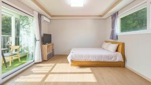 a bedroom with a bed and a large window at Gangneung Glad Pension in Gangneung