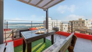 a balcony with a table and benches and the ocean at Gangneung Glad Pension in Gangneung