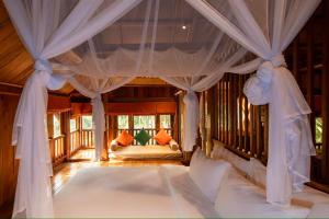a bedroom with a bed with curtains and a couch at Hang Mua Ecolodge in Ninh Binh +168 photos