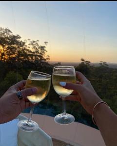 two people holding wine glasses with the sunset in the background at Romantic Stargazing Getaway - Beyond Bubbles in Kanimbla