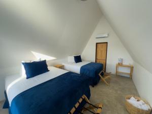 a bedroom with two beds with blue sheets at Arena Hostel in El Paredón Buena Vista