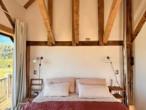 a bedroom with a bed with wooden ceilings and a window at Refugio del Sur, Escapada in Llanquihue