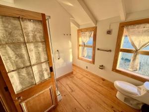 a bathroom with a toilet and a window and a door at Refugio del Sur, Escapada in Llanquihue +28 photos