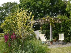 a garden with two chairs and a pergola and flowers at Maison Ville - Plage - Concarneau in Concarneau