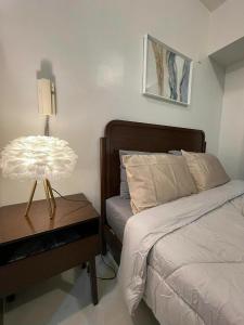 a bedroom with a bed and a table with a lamp at New Cozy Studio Apartment in Cebu City