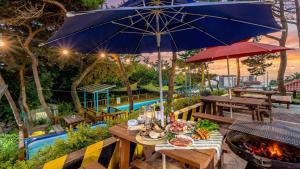 a table with food and an umbrella and a grill at Yeongheungdo J Pension in Incheon
