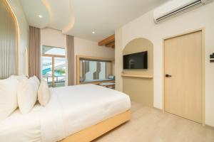 a bedroom with a white bed and a television at De Lunar Kohlarn in Ko Larn