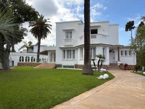 a white house with palm trees in the yard at Palais Elya in Rabat