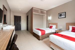 a hotel room with two beds and a bathroom at RedDoorz Plus at Hotel Ulin Samarinda in Samarinda