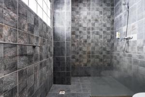 a bathroom with a shower with gray tiles at RedDoorz Plus at Hotel Ulin Samarinda in Samarinda +29 photos