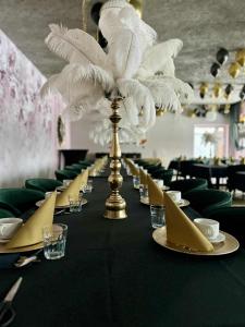 a long black table with a white feather centerpiece on it at Lubiński Resort in Stężyca