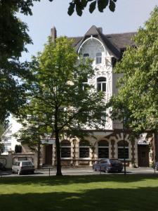 a large white house with cars parked in front of it at Hotel Antoni in Bochum