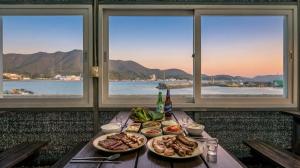 a table with plates of food on it with windows at tongyeong haegando pension in Tongyeong