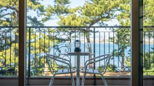a table and chairs on a balcony with a view of the water at tongyeong haegando pension in Tongyeong