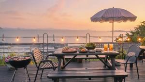 a table and chairs on a deck with an umbrella at Yeosu Eoneumeosjinnal Pension in Yeosu