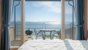 a bedroom with a balcony with a table and chairs at Yeosu Eoneumeosjinnal Pension in Yeosu +2 photos