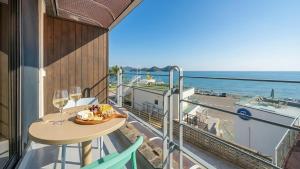 a balcony with a table with wine glasses and a boat at Yeosu Eoneumeosjinnal Pension in Yeosu