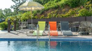a group of chairs and an umbrella next to a pool at Yeosu Eoneumeosjinnal Pension in Yeosu