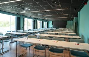 an empty classroom with tables and chairs and windows at Thon Hotel Brønnøysund in Brønnøysund