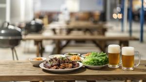 a table with plates of food and two glasses of beer at Goseong Jjun Camping Pension in Goseong