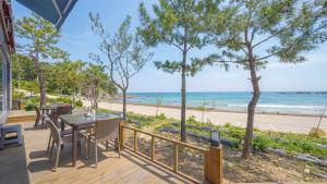 a deck with a table and chairs and a view of the beach at Pohang Playbeach Poolvilla in Pohang