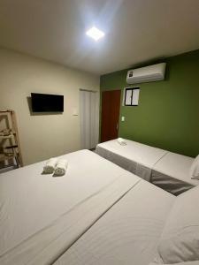 two beds in a room with green walls at Pousada Oxente Carioca in João Pessoa
