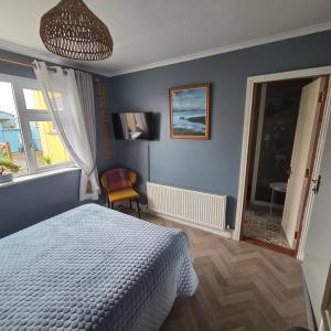 a bedroom with blue walls and a bed and a window at Salmon island view in Dromineer