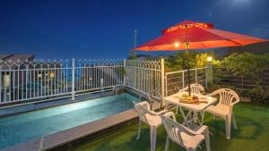 a table and chairs with an umbrella on a balcony at Geojedo Pilos Ocean View Pension in Geoje
