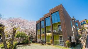 an office building withakura trees in front of it at Geojedo Pilos Ocean View Pension in Geoje