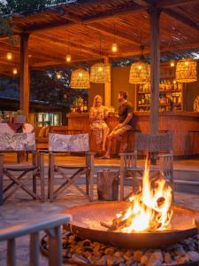 two people sitting in a bar with a fire pit at Klaserie Drift Misava in Klaserie Private Nature Reserve
