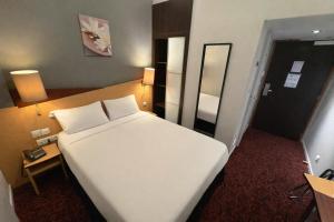 a hotel room with a white bed and a mirror at Kyriad Hotel Dijon Centre Gare in Dijon