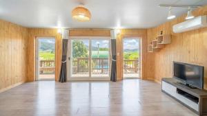 a living room with a television and a balcony at Ganghwa Herb Pension in Incheon