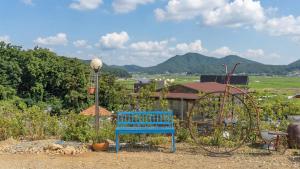 a blue bench and aokedoked wheel in a yard at Ganghwa Herb Pension in Incheon +1 photo