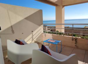 a balcony with white chairs and a blue table at L'Infini Bleu in Sète