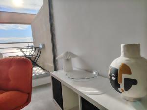 a living room with a chair and a vase on a desk at L'Infini Bleu in Sète