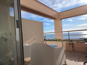 a balcony with a white chair and a view of the ocean at L'Infini Bleu in Sète