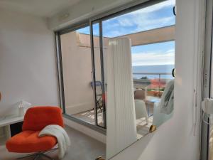 a room with a red chair and a balcony at L'Infini Bleu in Sète