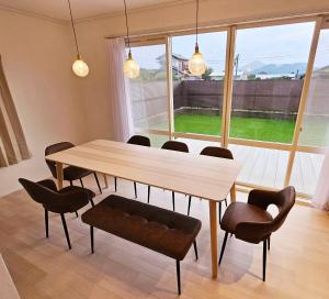 a dining room table and chairs with a large window at Itoshima STAY YAMAGA Keya in Itoshima