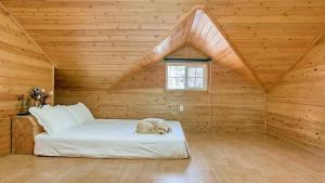 a cat sleeping on a bed in a wooden room at Youngheungdo Roma Spa Pension in Incheon