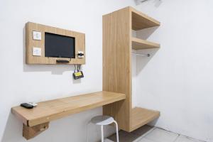 a wooden desk with a tv on a wall at Urbanview Hotel Cozy Samarinda by RedDoorz in Samarinda