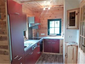 a small kitchen with red cabinets and a window at Götschlhütte in Bad Sankt Leonhard im Lavanttal