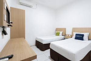 a hotel room with two beds and a television at Urbanview Hotel Cozy Samarinda by RedDoorz in Samarinda