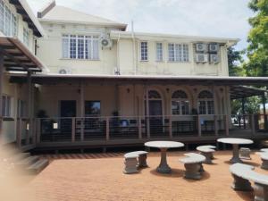a patio with tables and stools in front of a building at Concord Christian Guesthouse in Durban