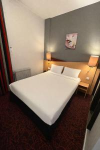 a large white bed in a room with two lamps at Kyriad Hotel Dijon Centre Gare in Dijon