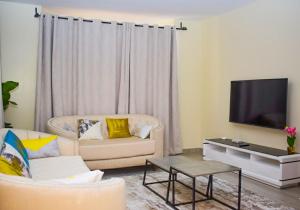 a living room with a couch and a tv at Zinari Comfort Homes in Nakuru