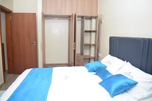 a bedroom with a bed with blue pillows on it at Zinari Comfort Homes in Nakuru