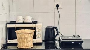 a kitchen counter with a microwave and a basket at BOHO Living Kochi Airport in Cochin