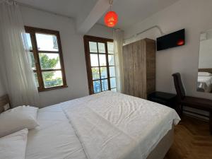 a bedroom with a large white bed and two windows at Akmonya Pansiyon in Eriklice
